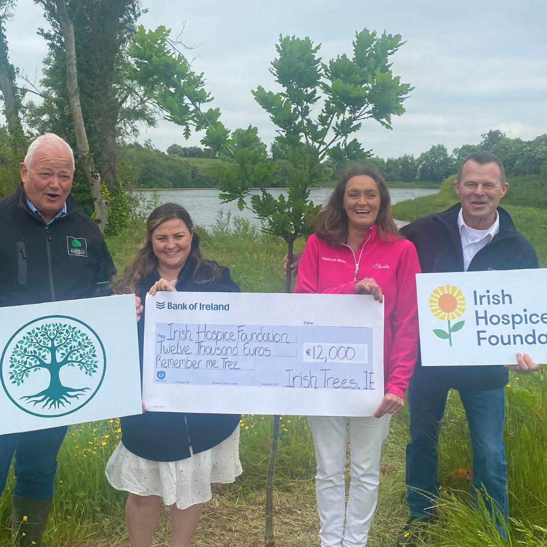 4 people - 2 men 2 women hold a cheque for €12,000 in front of the lake at irishurns.ie in support of the Irish Hospice foundation