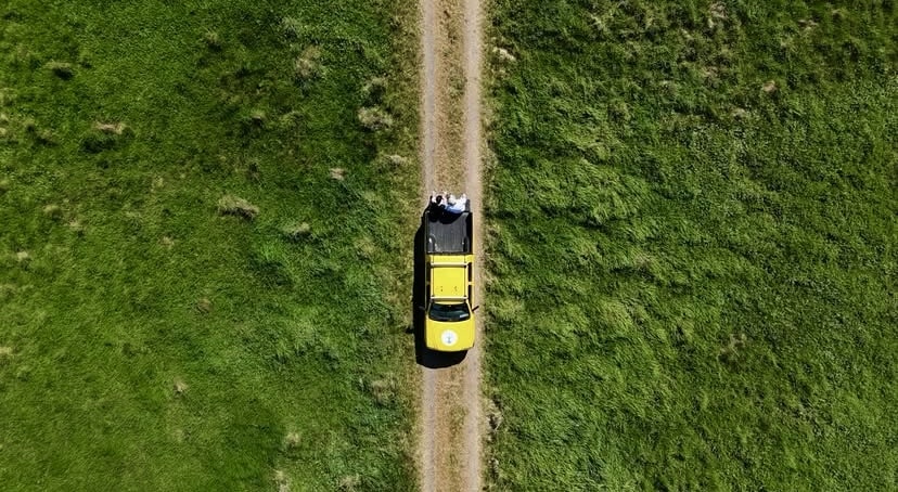Irish Trees yellow pickup truck driving down road between rewilding lands taken by drone from above